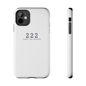 May include: White phone case with black camera and button details. The case features the number "222" in a dark font, with the words "trust the process" below it. The case is shown from the front and side.