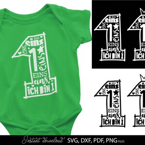 Schwarzes typografisches Design mit der Zahl 1 in kreativer Schriftgestaltung und kleinen Sternen sowie Herzsymbolen, kombiniert mit dem Text „Ich bin 1“ und mehrfach wiederholtem Wort „eins“. Das Motiv ist auf einem hellblauen Babybody dargestellt und zusätzlich in verschiedenen Farbvarianten als Grafik gezeigt. Perfekt geeignet für den ersten Geburtstag eines Kindes, für DIY Projekte wie Kleidung, Deko oder personalisierte Geschenke zur Feier des ersten Lebensjahres.