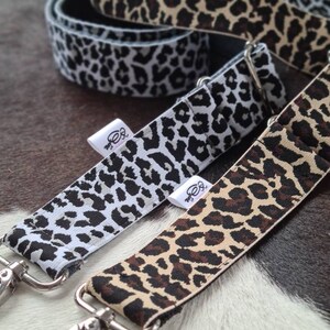 May include: Three different leopard print straps with silver clasps. The straps are made of fabric and have a black, white, and brown leopard print.