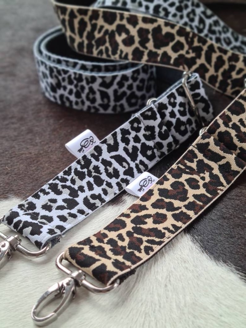 May include: Three different leopard print straps with silver clasps. The straps are made of fabric and have a black, white, and brown leopard print.