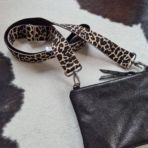 May include: A black leather purse with a leopard print adjustable strap. The strap is made of a black and brown fabric with a leopard print pattern.