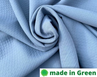 Puede incluir: Primer plano de una tela azul claro con una textura de tejido de gofre. La tela está doblada y drapeada, mostrando su textura suave y fluida.