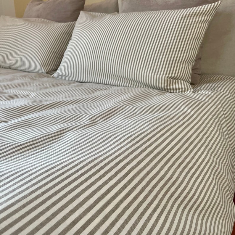 Puede incluir: Un juego de cama a rayas blancas y grises con una funda n&oacute;rdica y dos fundas de almohada.