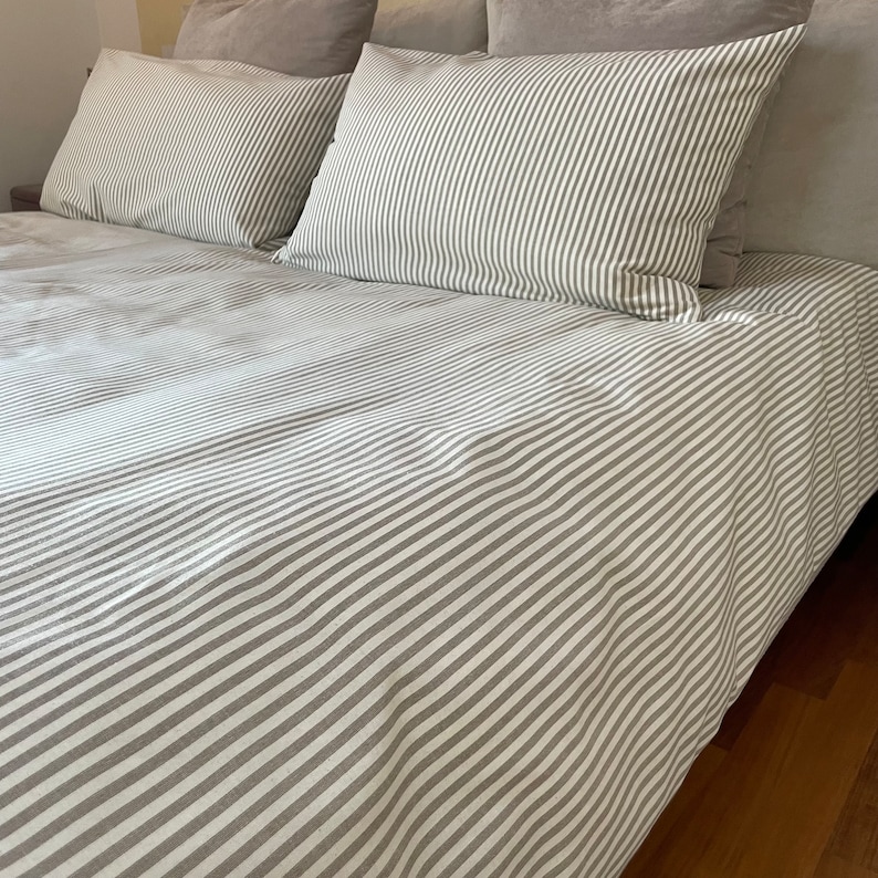 Puede incluir: Un juego de cama a rayas blancas y grises con una funda n&oacute;rdica y dos fundas de almohada.
