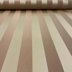 Könnte beinhalten: Eine Stoffrolle mit vertikalen Streifen in Beige-, Hellbraun- und Brauntönen. Der Stoff hat einen dezenten Glanz, der auf eine satin- oder seideartige Textur hindeutet. Die Streifen sind unterschiedlich breit und erzeugen ein ansprechendes Muster.