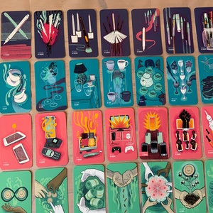 Pu&ograve; includere: Un set di 30 carte illustrate con vari disegni, tra cui un cuore con penne, una lampada con bicchieri, un telefono con fuoco e una mano con una moneta. Le carte sono tutte rettangolari e hanno un bordo bianco.