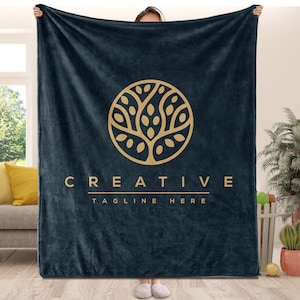 May include: A dark blue fleece blanket with a gold tree logo and the text "CREATIVE TAGLINE HERE".