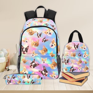 May include: A backpack, lunch bag, and pencil case set. The bags feature a colorful, iridescent background with a repeating pattern of cat and dog faces. The backpack has a black mesh side pocket and a black handle. The lunch bag has a black handle. The pencil case is rectangular.