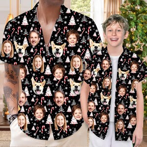 May include: Black short-sleeved shirt featuring a repeating pattern of faces, dogs, Christmas trees, candy canes, and snowflakes. The shirt is worn by a man and a child. A Christmas tree is visible in the background.