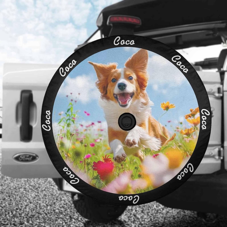 May include: Black spare tire cover with a white border and the word "Coco" repeated around the edge. The center of the cover features a colorful image of a dog running through a field of flowers.