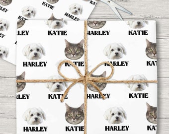 May include: White wrapping paper with a repeating pattern of a cat and a dog's face. The names "Katie" and "Harley" are printed below each animal's face.
