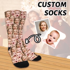 May include: A pair of white socks with a custom design featuring multiple faces. The socks are shown on a wooden surface with the text "CUSTOM SOCKS" above them.