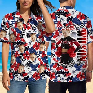 May include: Short-sleeved button-down shirt with a floral pattern in red, white, and blue. The shirt features a repeating pattern of faces and the name "Wilson" on the back, along with a cheerleader graphic and the words "Twelve Bridges".