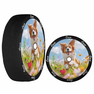 May include: Two black spare tire covers with a colorful image of a dog running through a field of flowers. The dog is brown and white with floppy ears and a happy expression. The words "Coco" are repeated around the edge of each cover.
