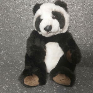 Op de afbeelding: Een zwart-witte pluche pandabeer met bruine poten. De panda zit met gekruiste benen en heeft een vriendelijke uitdrukking.