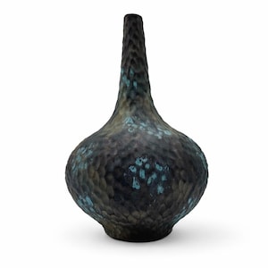 May include: A textured, dark-colored vase with a bulbous base and a slender neck. The vase has a mottled appearance with hints of teal and blue, creating a unique, aged aesthetic. The vase is likely made of ceramic or a similar material.