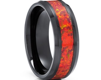 May include: A black ring with a vibrant, fiery red-orange center. The ring has a polished, glossy finish, and the center stone appears to be a mosaic of colors. The ring's design is modern and eye-catching, suitable for everyday wear or special occasions.