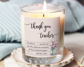 Op de afbeelding: Een witte kaars met een roze label waarop "thank you teacher" staat. Het label bevat ook de tekst "Mrs Johnson, class 6M, 2021, Dear Mrs. thank you so much for all of your help and support. With love, Anne".