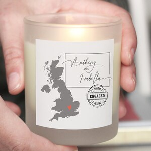 May include: A white frosted glass candle with a label featuring a grey map of the United Kingdom with a red heart over London. The label also includes the text "Anthony and Isabella" and a red stamp that says "London Engaged"