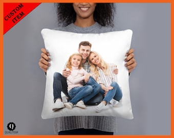 May include: White cushion with a printed image of a family of three. The family are sitting on a white background and smiling. The father is wearing a blue shirt and jeans, the mother is wearing a striped shirt and jeans, and the daughter is wearing a pink shirt and jeans.