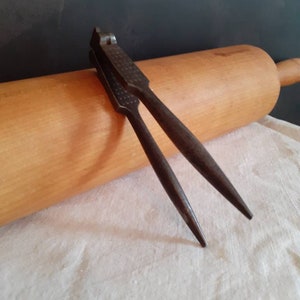 Peut inclure: Un casse-noisette en métal vintage avec une surface texturée. Le casse-noisette est ouvert et prêt à casser des noix.