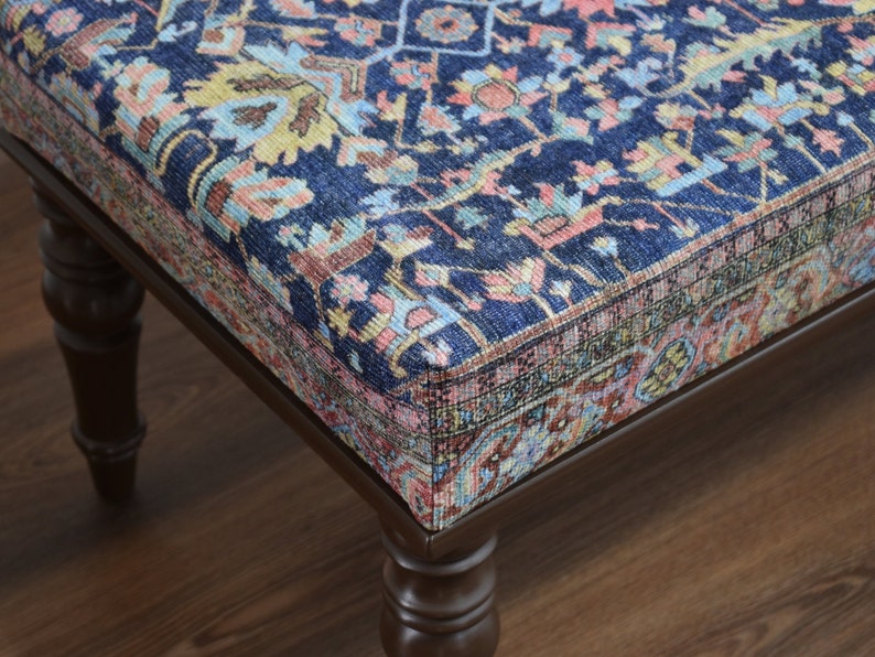 May include: A dark blue ottoman with a patterned fabric top and dark brown wooden legs.
