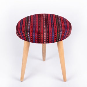 May include: A red and blue patterned stool with three wooden legs.