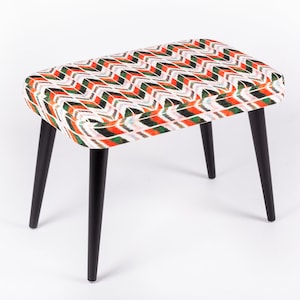 May include: A small, rectangular ottoman with black legs and a white, orange, and green geometric pattern.