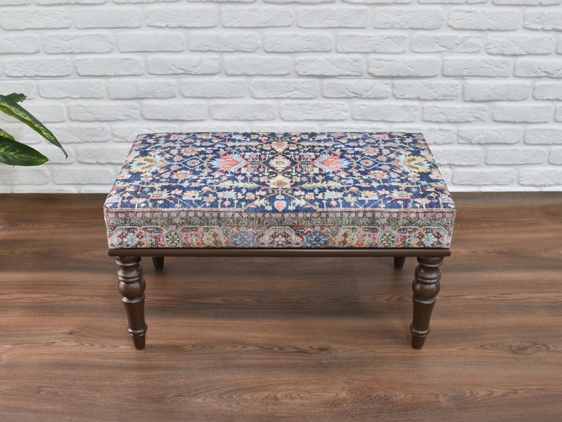 May include: A dark wood ottoman with a patterned fabric top. The fabric features a blue background with a colorful floral design.