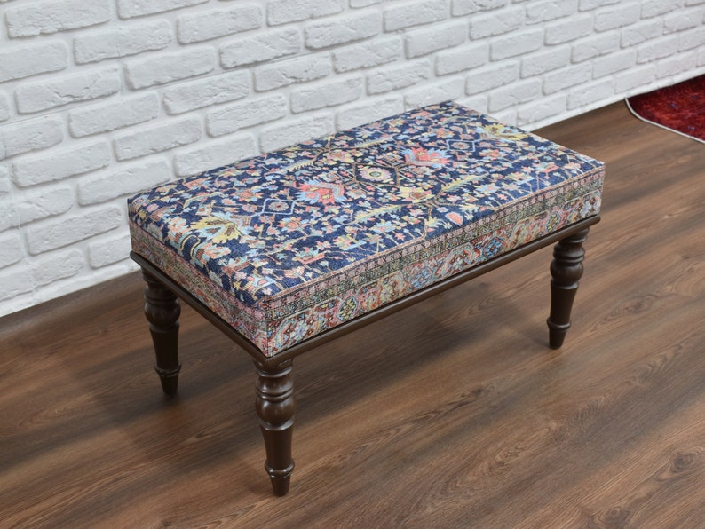 May include: A wooden bench with a dark blue and floral patterned cushion. The bench has four turned legs and a rectangular top.