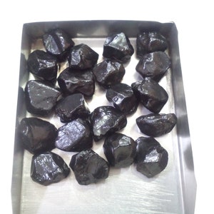 May include: A tray of loose black gemstones. The gemstones are various sizes and shapes, with a shiny, polished finish.