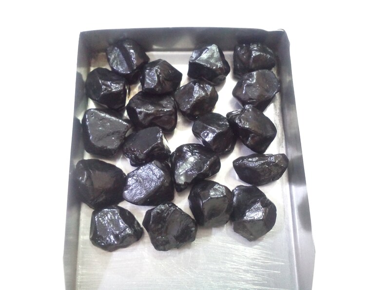 May include: A tray of loose black gemstones. The gemstones are various sizes and shapes, with a shiny, polished finish.