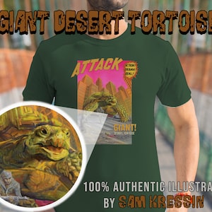 Może przedstawiać: Zielony T-shirt z grafiką przedstawiającą gigantycznego pustynnego żółwia atakującego miasto. Grafika jest w stylu komiksowym z napisami "Attack!" i "Giant! Desert Tortoise" w kolorze czerwonym i białym. Tekst "100% Authentic Illustration by Sam Kressin" jest nadrukowany brązowym kolorem na dole koszulki.