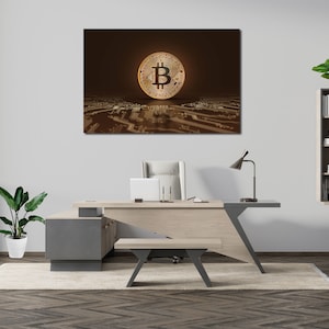 May include: A modern office interior with a desk, chair, and a large framed print of a gold Bitcoin on a brown background. The print is hanging on a white wall above the desk. There is a small plant on the floor to the left of the desk.