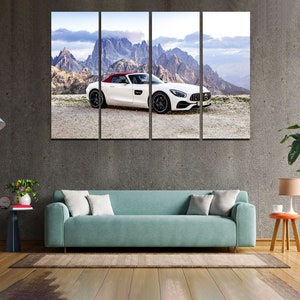 May include: A white convertible sports car with a red roof is parked on a road with a mountain range in the background. The car is facing the camera and the mountains are in the distance.