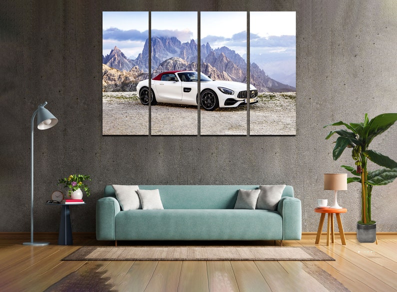 May include: A white convertible sports car with a red roof is parked on a road with a mountain range in the background. The car is facing the camera and the mountains are in the distance.