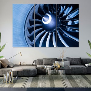 Könnte beinhalten: Eine Nahaufnahme eines Düsentriebwerks mit einem blauen und silbernen Farbschema. Das Triebwerk besteht aus vielen Schaufeln, die in einem kreisförmigen Muster angeordnet sind. Die Schaufeln zeigen alle in die gleiche Richtung und sind alle sehr scharf.