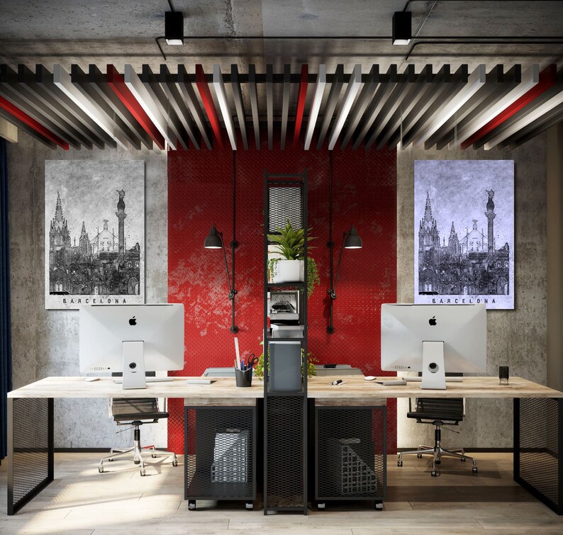 May include: Two black and white images of Barcelona, Spain, hang on a red wall in a modern office. Two desks with black metal frames and black mesh shelves are in the center of the room. Each desk has a silver computer monitor and a black office chair.