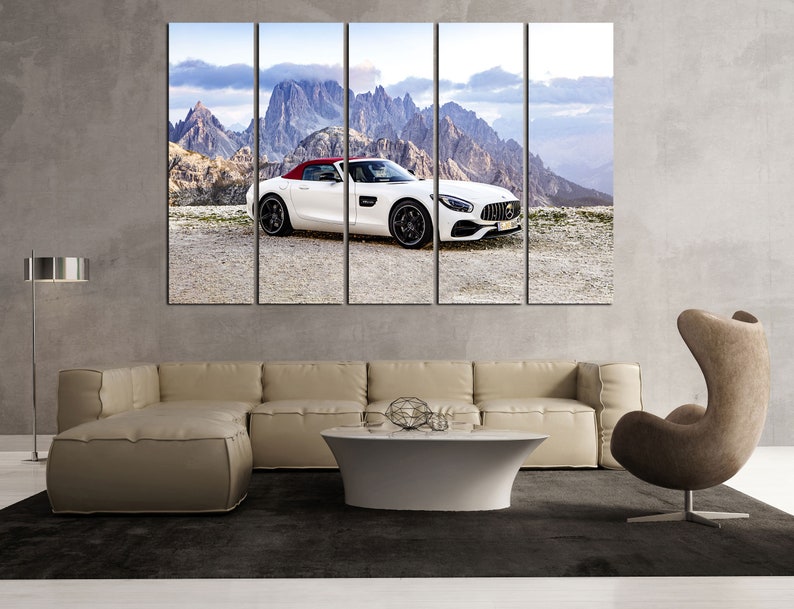 May include: A white convertible sports car with a red interior is parked on a mountain road with a view of snow-capped peaks in the background.