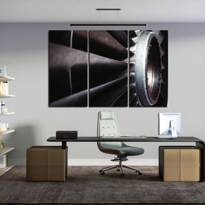Könnte beinhalten: Ein dreiteiliger Leinwanddruck einer Nahaufnahme eines Düsentriebwerkslüfters. Die Lüfterblätter sind silber und schwarz, und das Bild ist scharf. Die Leinwand hängt an einer Wand in einem modernen Büro.