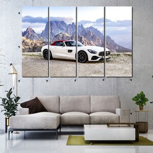 May include: A white convertible sports car with a red roof is parked on a dirt road in front of a mountain range. The car is facing the camera and the mountains are in the background.