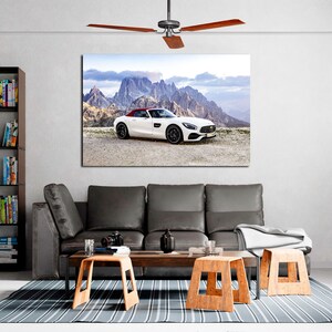 May include: A white convertible sports car parked on a mountain road with a view of the mountains in the background. The car has a red interior and a black roof.