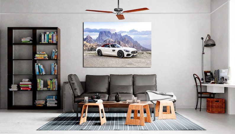 May include: A white convertible sports car parked on a mountain road with a view of the mountains in the background. The car has a red interior and a black roof.
