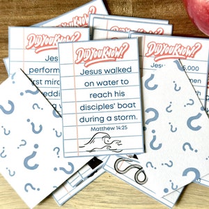May include: A set of white cards with blue question marks and the text "Did You Know?" in red and black. Each card has a different Bible verse about Jesus. The cards are on a wooden surface.