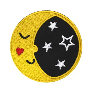 May include: Circular embroidered patch depicting a yellow crescent moon with a red heart and closed eyes, and a black background with white stars. The patch has a yellow border. Suitable for application on clothing or accessories.
