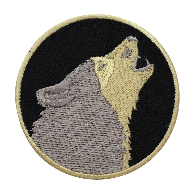 Pode incluir: Etiqueta bordada de um lobo cinzento a uivar para a lua. O lobo &eacute; delineado em uma cor marrom clara e &eacute; colocado sobre um fundo preto. A etiqueta &eacute; circular e tem uma borda marrom clara.