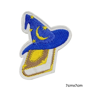 Op de afbeelding: Geborduurde patch met een blauwe tovenaars hoed met gele sterren en een maan, bovenop een bruin en geel boek. De patch is wit omrand. De afmetingen zijn 7 cm x 7 cm.