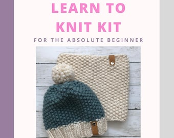 May include: Learn to knit kit for beginners, featuring a white and teal knitted hat with a pompom and a white knitted cowl. The kit includes two skeins of yarn, circular knitting needles, a stitch marker, a tapestry needle, and video instructions.