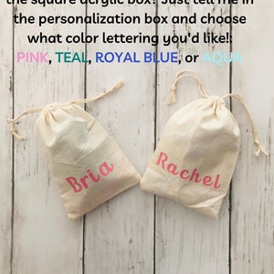 May include: Two white cotton drawstring bags with pink lettering. The bag on the left says "Bria" and the bag on the right says "Rachel".