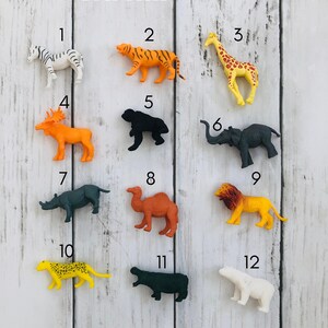 K&ouml;nnte beinhalten: Ein Set mit 12 Plastik-Safari-Tierfiguren, nummeriert von 1 bis 12. Die Tiere umfassen ein Zebra, einen Tiger, eine Giraffe, einen Elch, einen Gorilla, einen Elefanten, ein Nashorn, ein Kamel, einen L&ouml;wen, einen Leoparden, ein Flusspferd und einen Eisb&auml;ren.